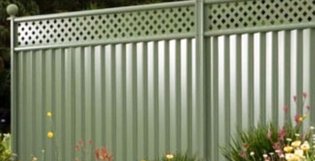 Light green Colorbond fence with lattice top surrounded by a vibrant garden in Canberra